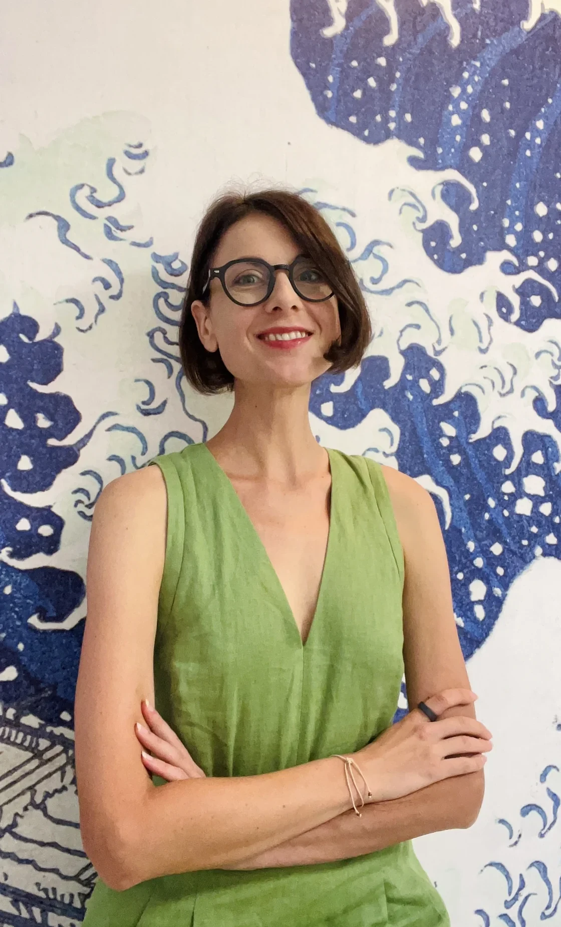 Andrea Maloney in a green dress, standing with her arms crossed